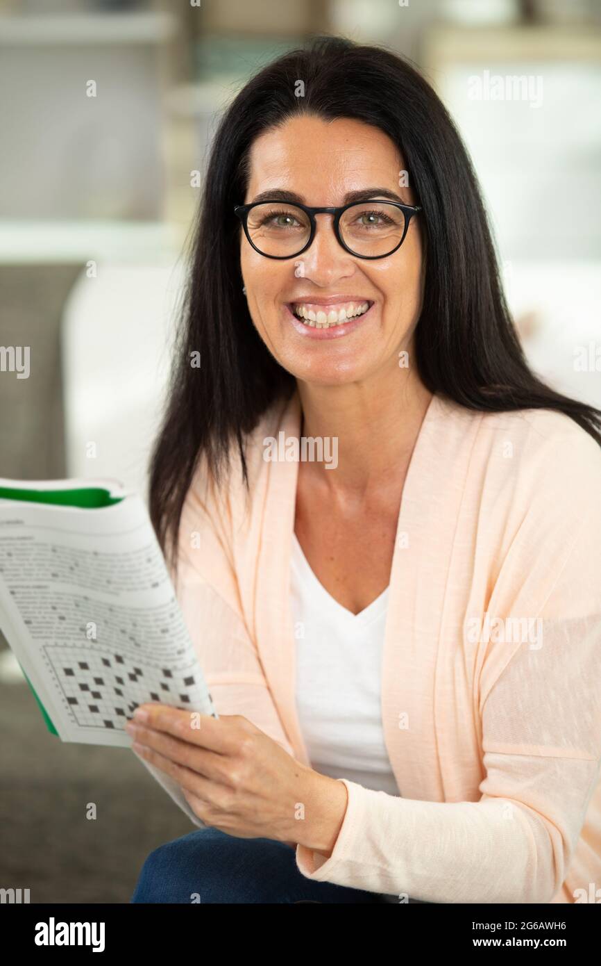 felice attraente donna che risponde crossword puzzle game Foto Stock