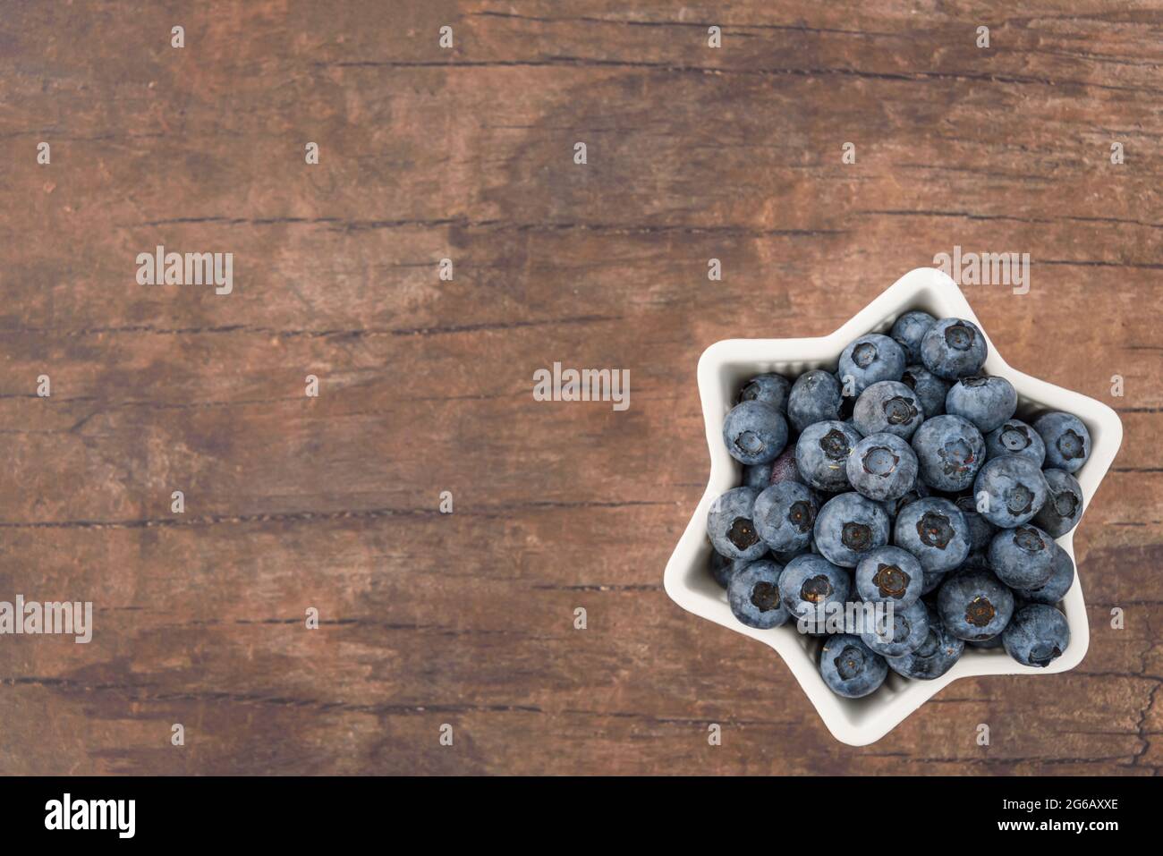 Mirtilli per il 4 luglio, mirtilli in ciotola a forma di stella, su sfondo di legno Foto Stock