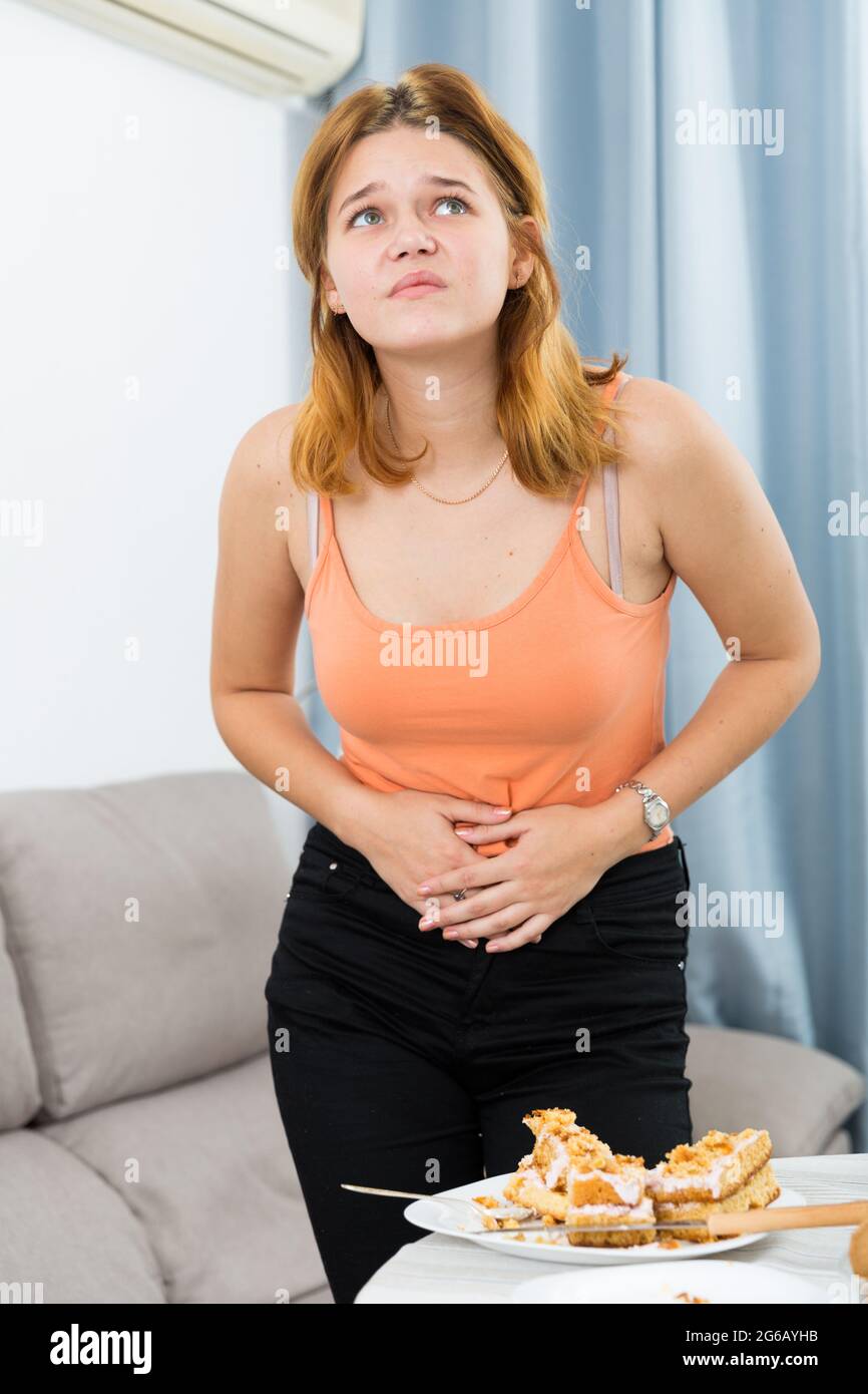 La giovane donna sta avendo un mal di stomaco dopo aver mangiato troppo  Foto stock - Alamy