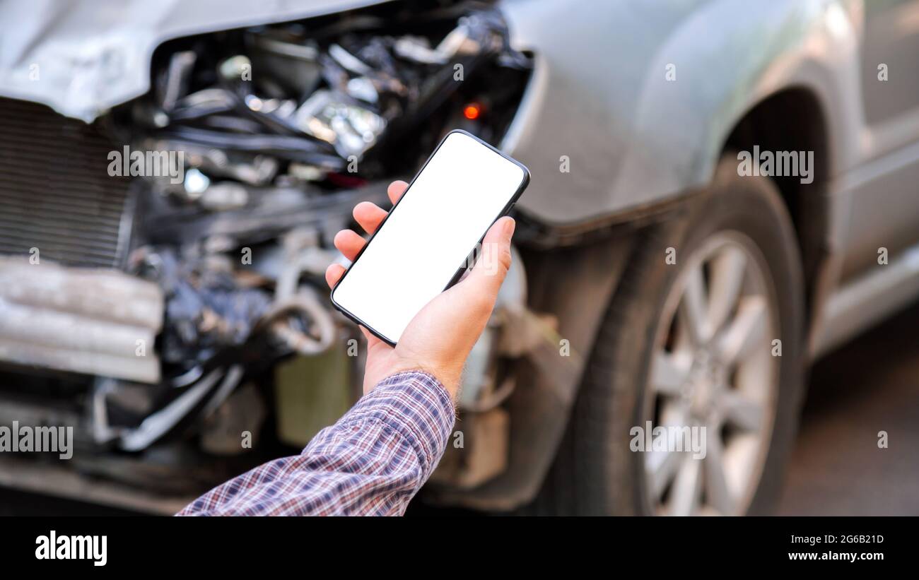 L'uomo tiene lo schermo bianco del telefono cellulare mockup nelle mani dopo un incidente d'auto. Chiamare il servizio di assicurazione nell'app web per il luogo dell'incidente d'auto. Smartphone in Foto Stock