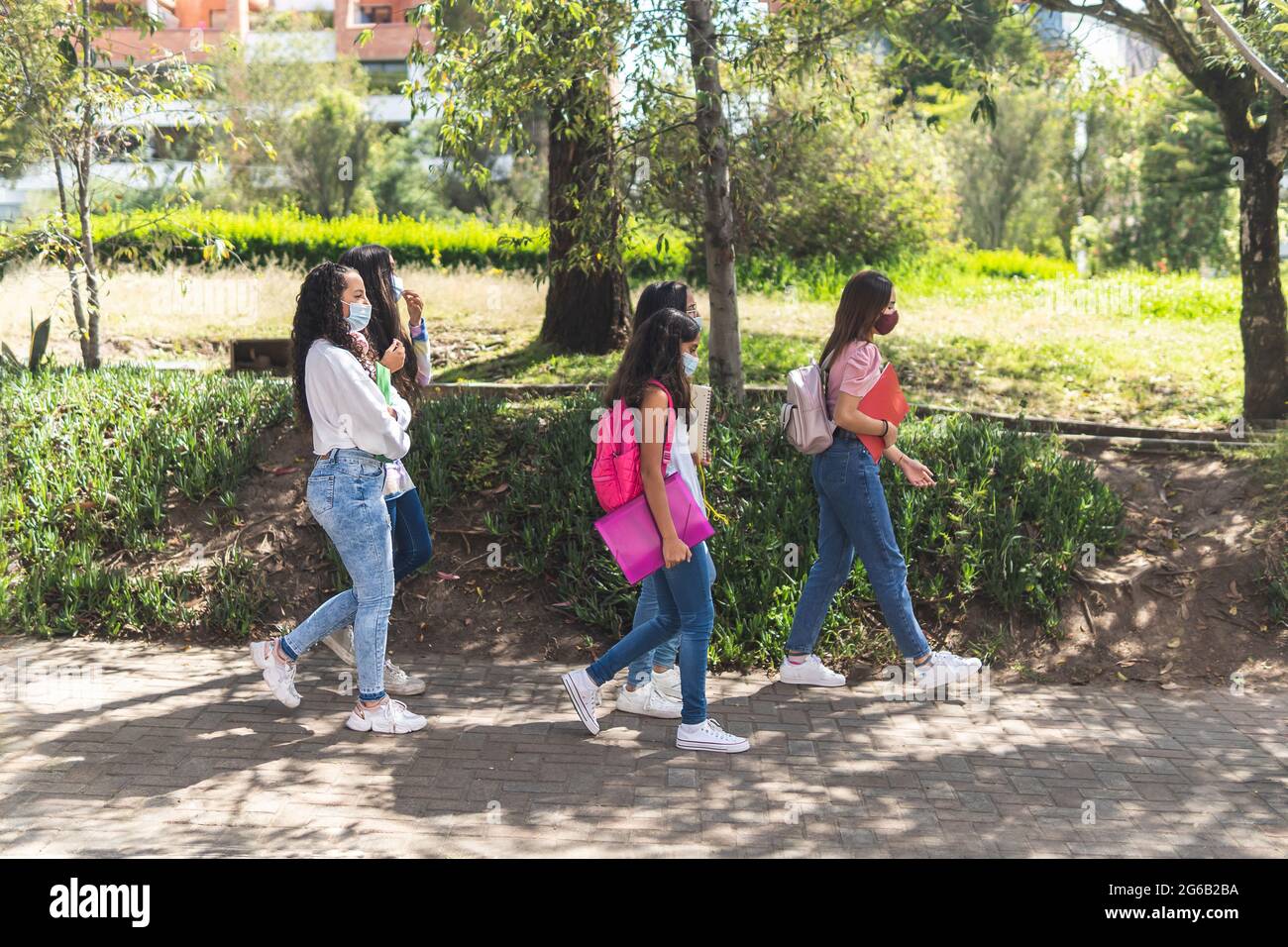 Un gruppo di adolescenti di Latina cammina per classe indossando maschere come prevenzione contro Coronavirus. Concetto di educazione e salute Foto Stock