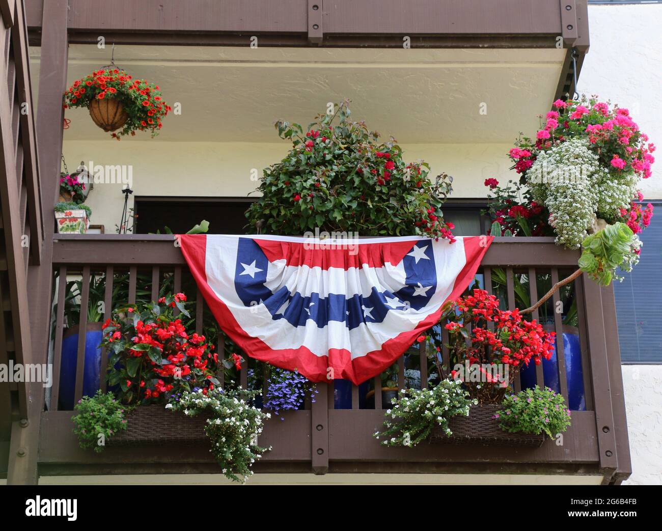 Un mazzetto bianco e blu luminoso con stelle e strisce pende dalla ringhiera di un piccolo balcone il giorno dell'Indipendenza, Monterey, CA. Foto Stock