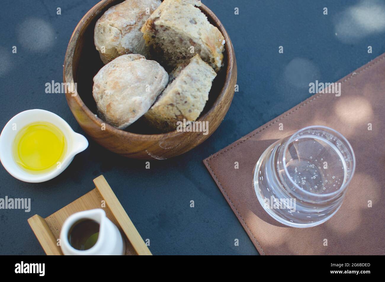 Vista panoramica di un cesto di pane, olio d'oliva e un bicchiere d'acqua frizzante Foto Stock