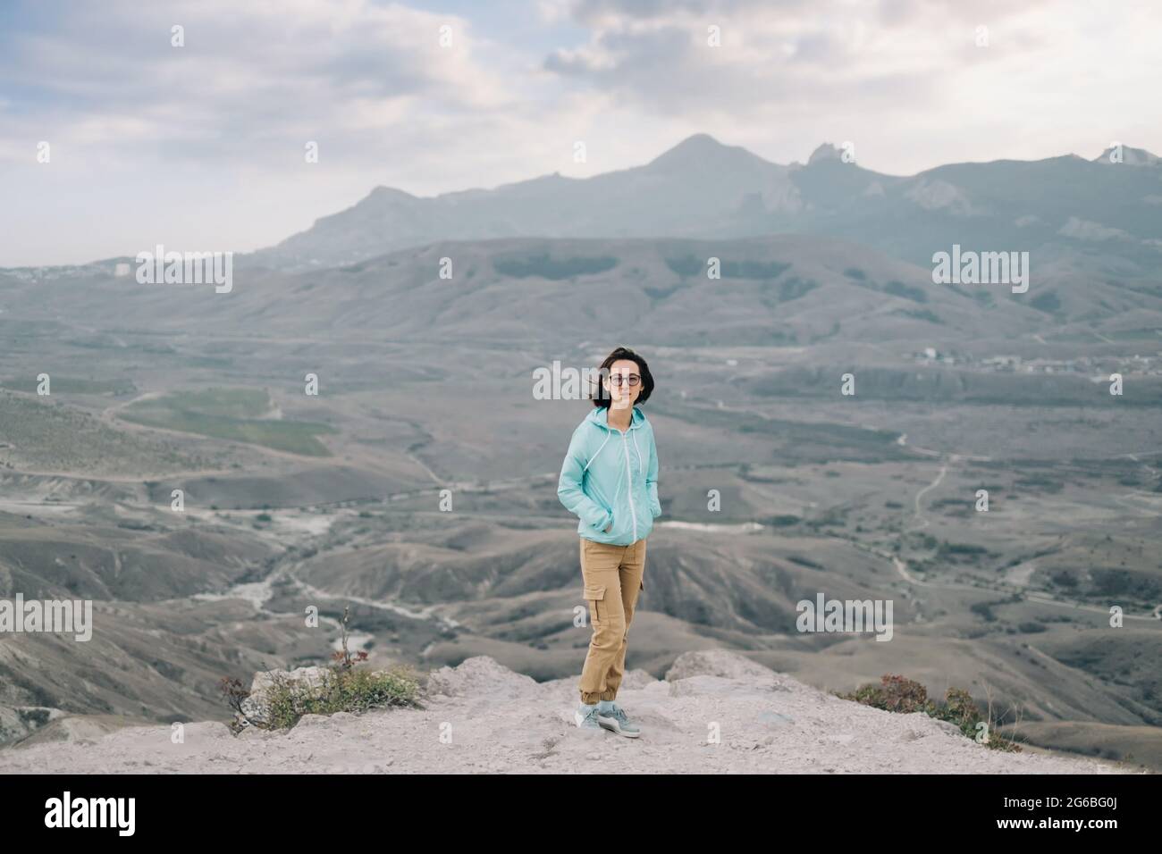 Donna si trova sullo sfondo di un paesaggio montano. Foto Stock