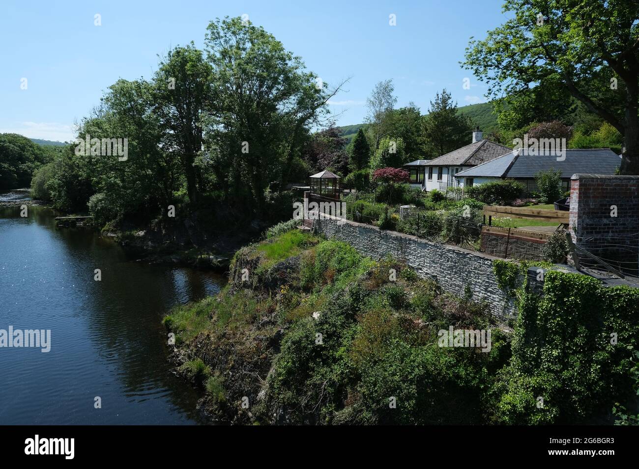 Idilliaca casa sul fiume con alberi e cielo blu Foto Stock