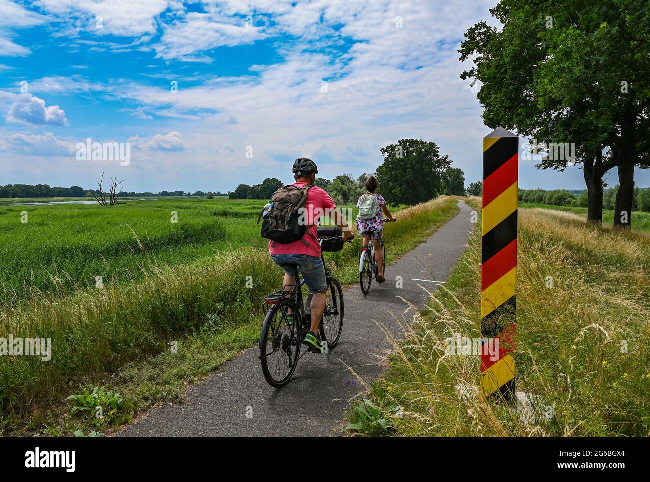 Reitwein, Germania. 04 luglio 2021. I ciclisti si trovano sulla pista ciclabile Oder-Neisse, che si trova nell'Oderbruch, sulla diga sul fiume Oder, confine tedesco-polacco, vicino a Reitwein. La pista ciclabile Oder-Neisse è una pista ciclabile a lunga percorrenza nella Repubblica Ceca e in Germania lunga circa 630 chilometri. Segue in gran parte il confine orientale della Germania con la Polonia. Credit: Patrick Pleul/dpa-Zentralbild/ZB/dpa/Alamy Live News Foto Stock