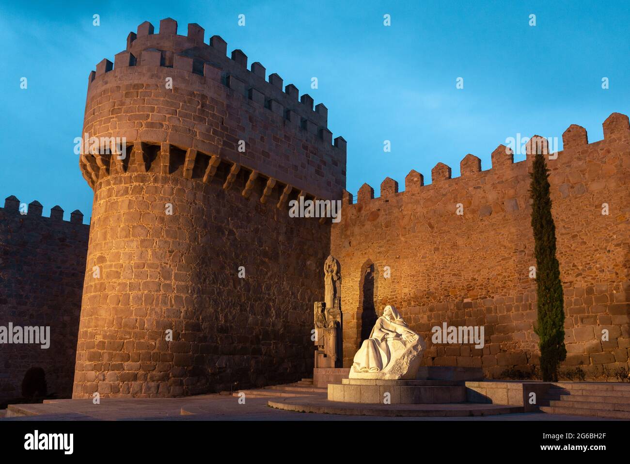 Statua di Santa Teresa di Gesù e le mura medievali della città di Avila al tramonto, Spagna Foto Stock