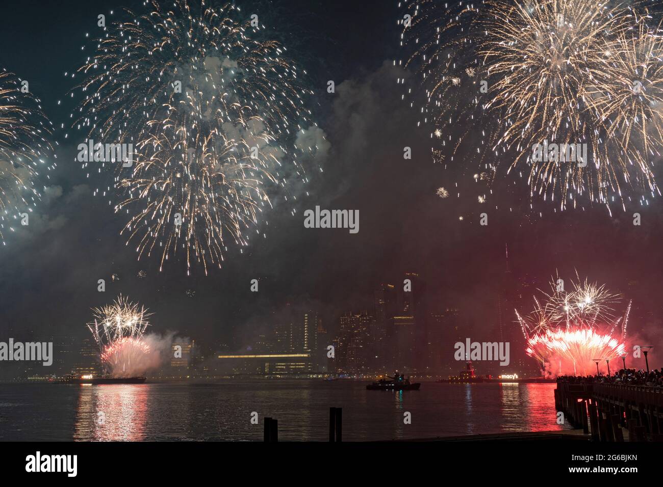 NEW YORK, NY - LUGLIO 04: Gli spettatori guardano i fuochi d'artificio esplodere durante il 45° anno Macy's 4 luglio mostra fuochi d'artificio che si affaccia sullo skyline di Manhattan al Gantry state Plaza a Long Island City il 4 Luglio 2021 nel quartiere Queens di New York City. La celebrazione di quest'anno è stata più ampia e prolungata, con una durata di 25 minuti, rispetto agli anni precedenti come prova del miglioramento della città rispetto al COVID-19. A causa della pandemia del coronavirus lo scorso anno, l'esposizione di fuochi d'artificio è stata distribuita su quattro notti e più comuni nel tentativo di limitare le riunioni e rallentare la diffusione. Credito: Ron Adar/Alamy Foto Stock