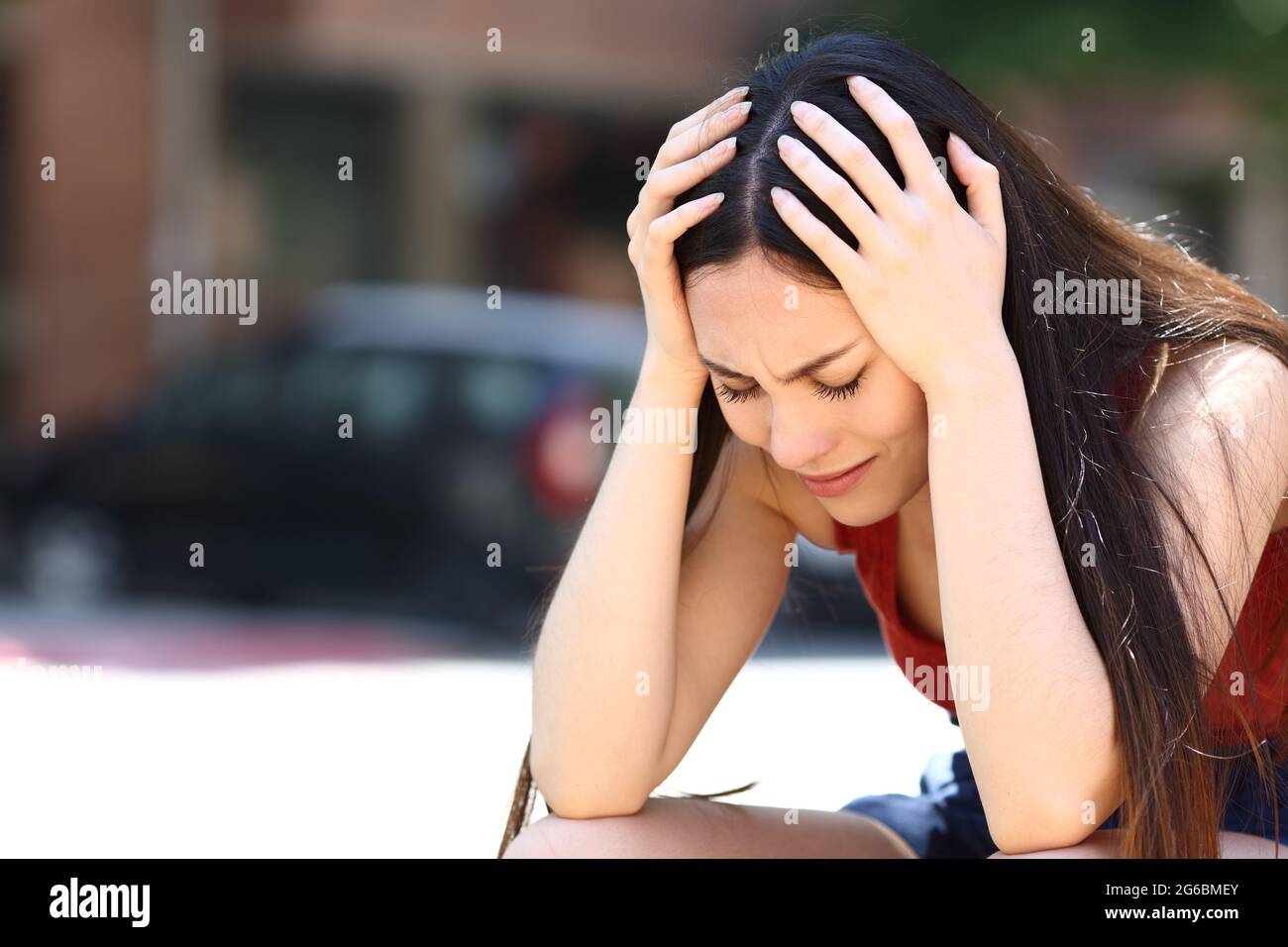 Triste donna asiatica che si lamenta da sola seduto in strada Foto Stock