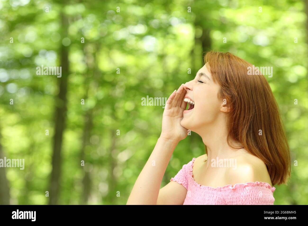 Vista laterale ritratto di una donna che grida forte in una foresta Foto Stock