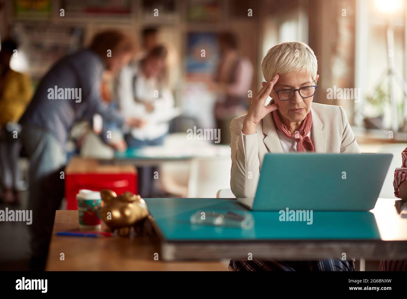 Un dipendente anziano di un ufficio femminile si concentra su un lavoro su un computer portatile in un'atmosfera di lavoro Foto Stock