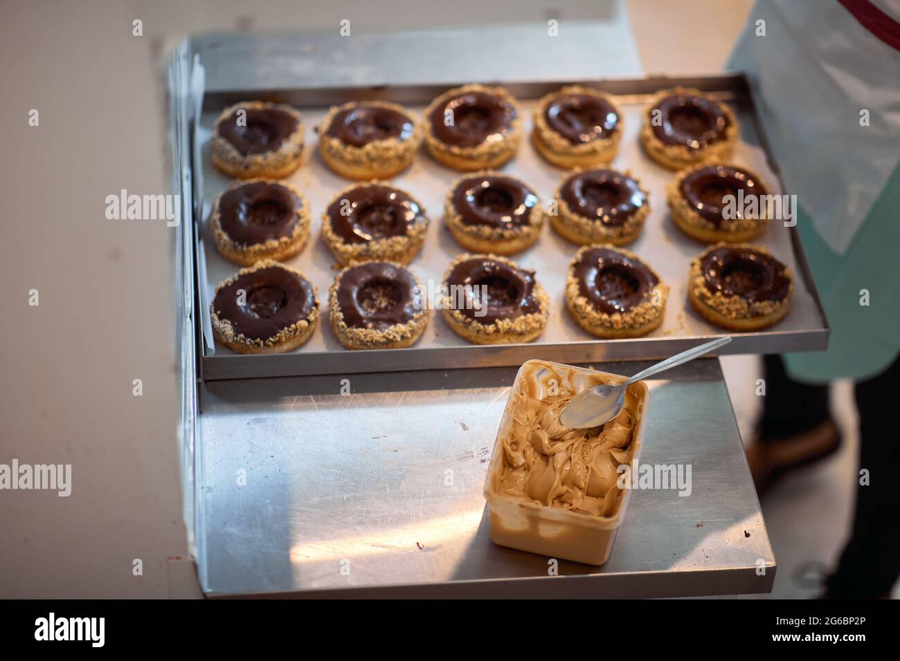Un vassoio pieno di deliziose ciambelle dall'aspetto irresistibile con burro di arachidi in un laboratorio di caramelle. Pasticceria, dessert, dolce, fare Foto Stock