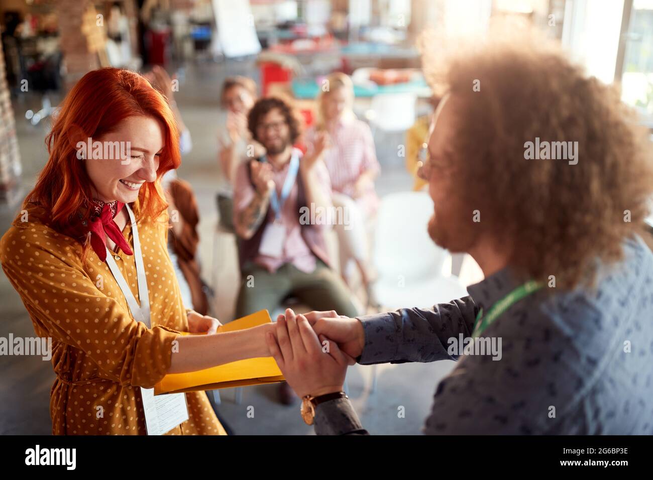 Una giovane e timida lavoratrice d'ufficio sta ottenendo il premio aziendale in un'atmosfera piacevole Foto Stock