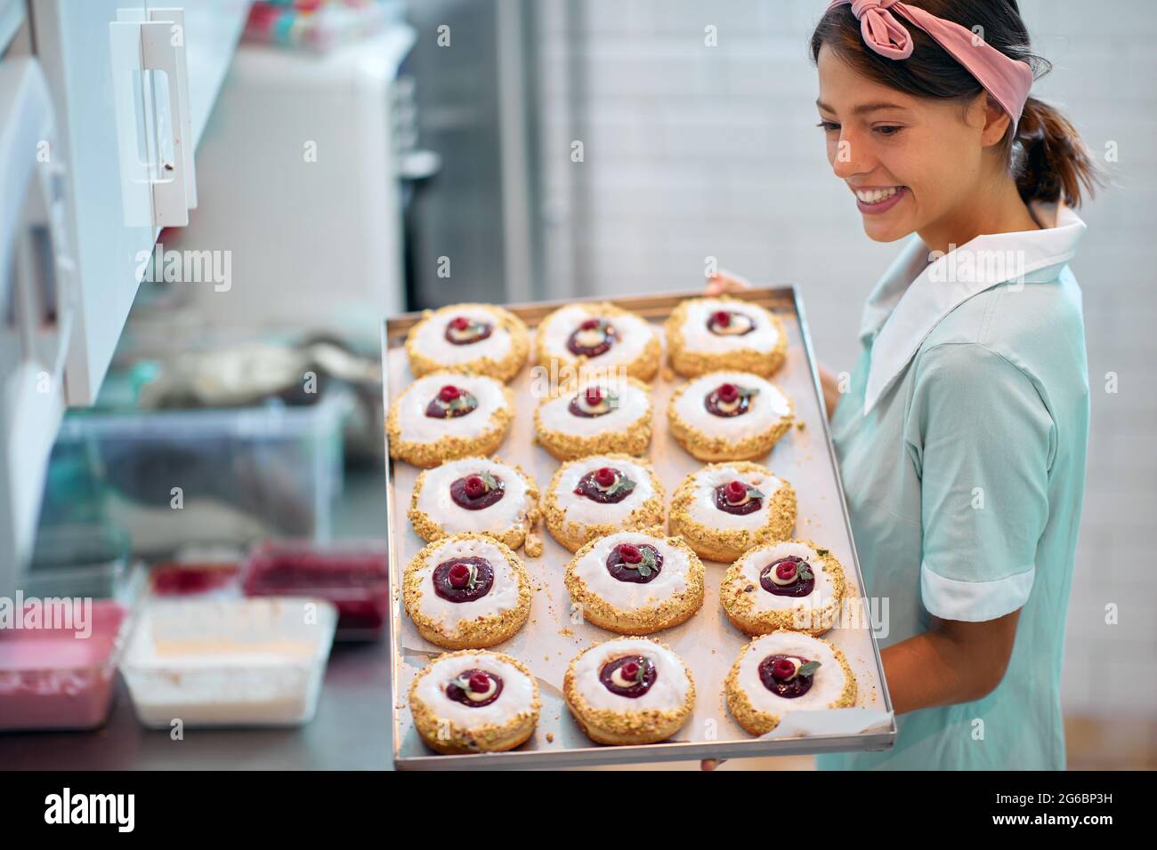 Una giovane donna di piccola impresa è appassionata circa le sue ciambelle squisite fatte a mano di aspetto irresistibile. Pasticceria, dessert, dolce, fare Foto Stock