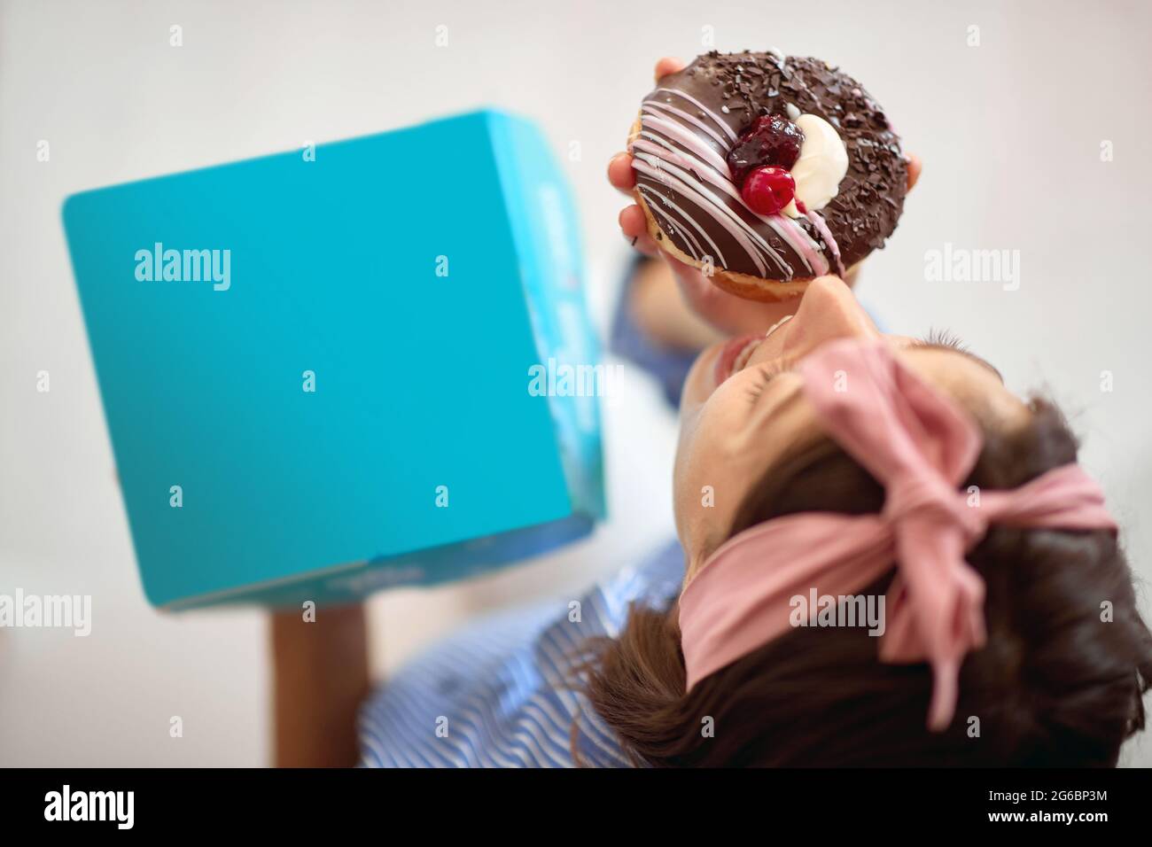 Donna felice che mangia deliziose ciambelle a casa Foto Stock