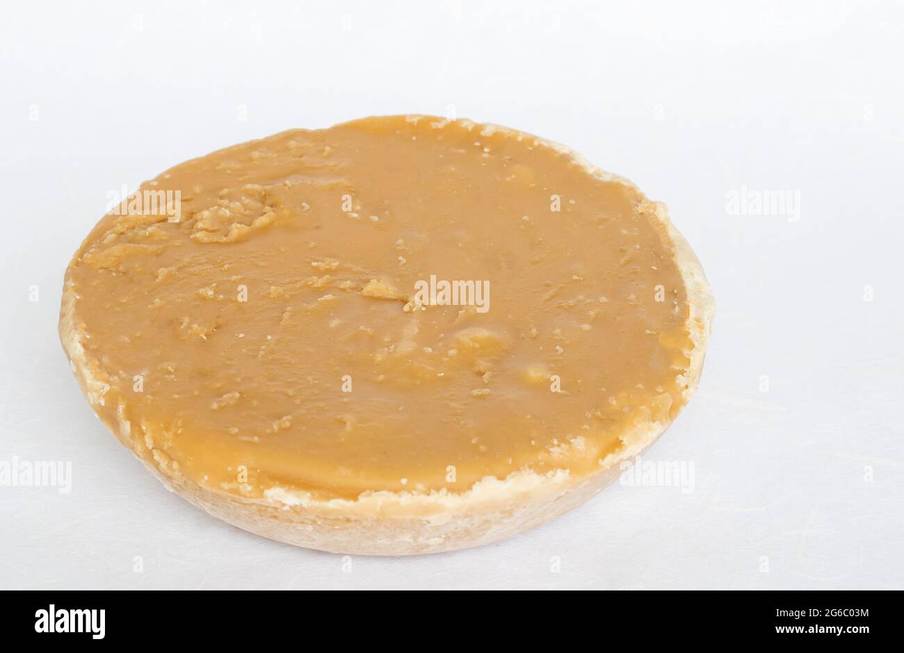 La forma circolare dello zucchero di cocco ha un colore marrone chiaro, su sfondo bianco. Spazio di copia. Foto Stock