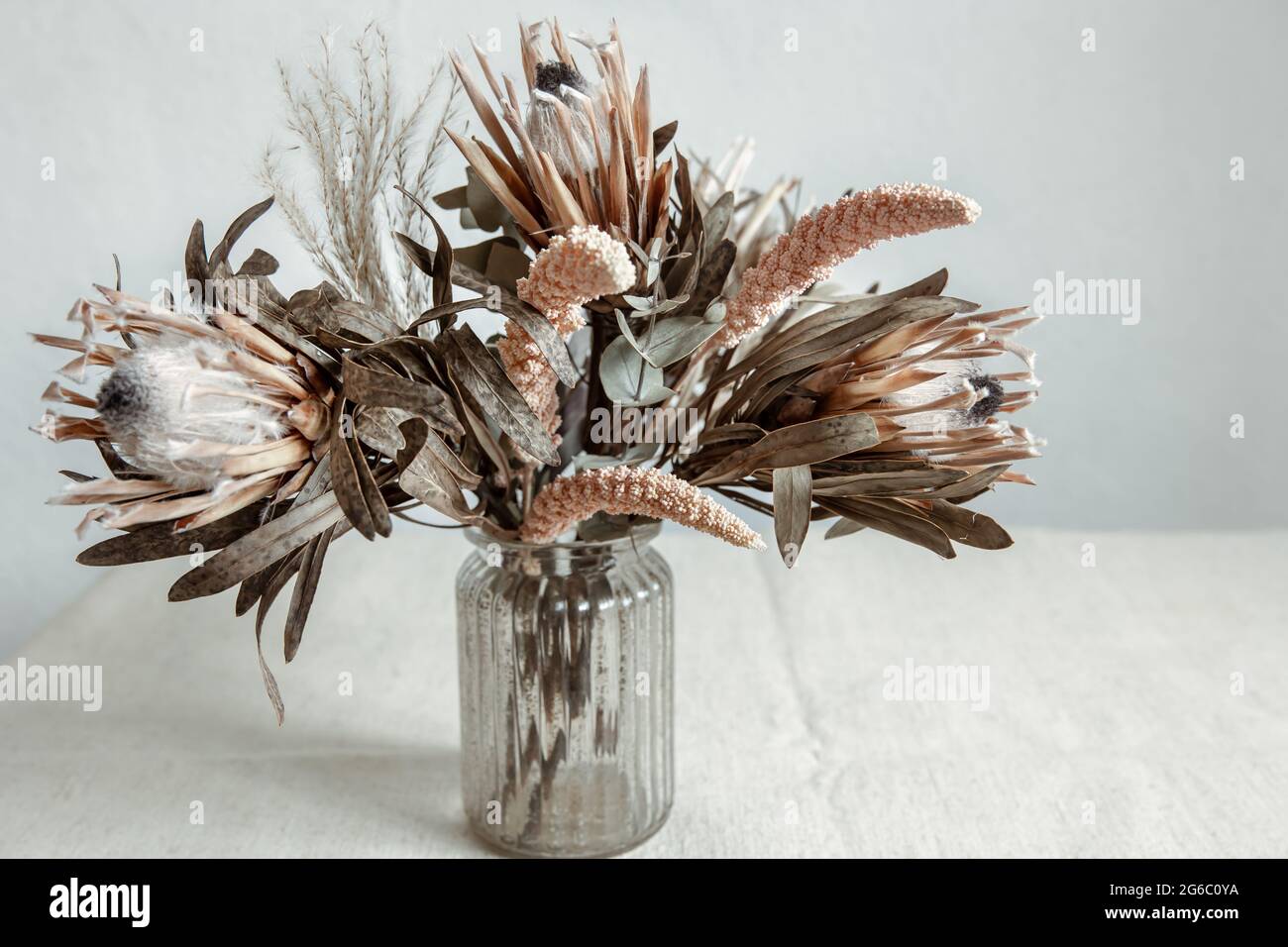 Un bouquet di fiori secchi in vaso di vetro su sfondo chiaro. Foto Stock