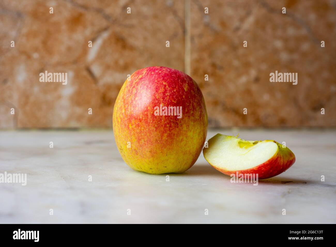 Primo piano di una mela con una fetta su uno sfondo di marmo. Foto Stock
