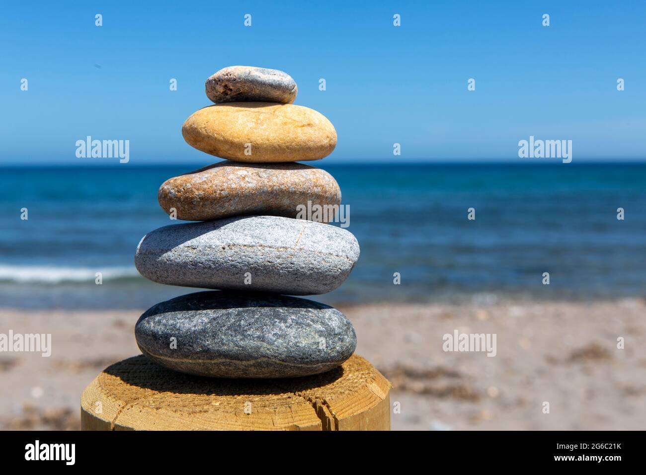 equilibrio e bellezza in forma piramidale di cinque pietre poste in equilibrio uno sull'altro, di fronte al mare, dando pace e armonia visiva. Foto Stock