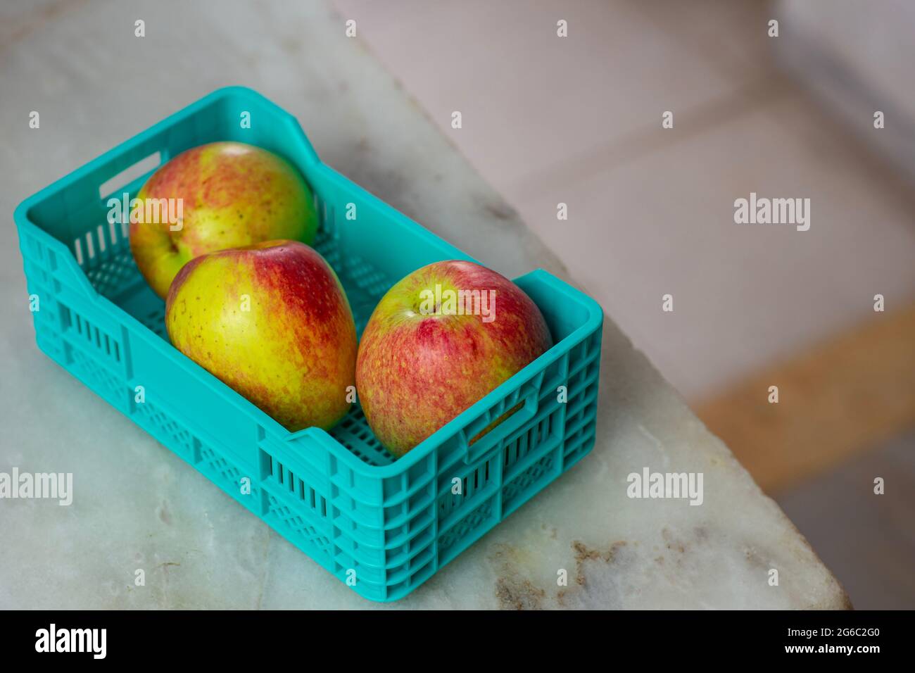 Vista dall'alto delle mele in una cassa di plastica su uno sfondo di marmo. Foto Stock