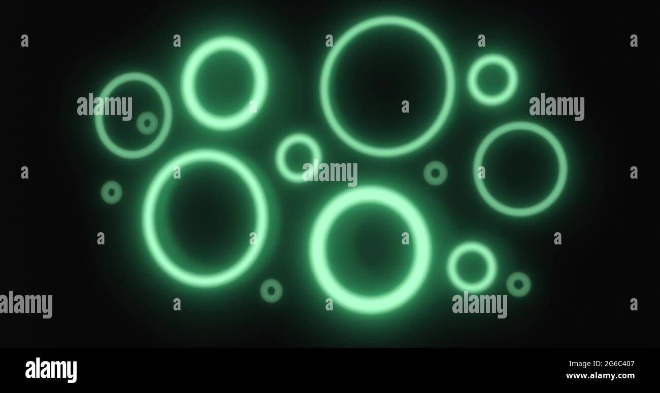 Gli anelli al neon verdi pulsante di varie dimensioni si illuminano su sfondo nero Foto Stock