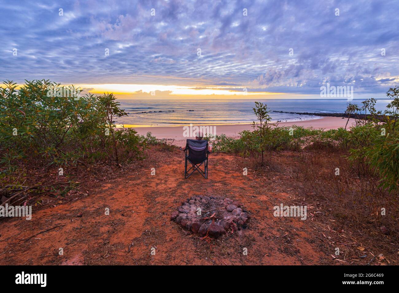 Persona seduta su una sedia che contempla l'alba sulla spiaggia, Pender Bay Escape, Dampier Peninsula, Australia Occidentale, WA, Australia Foto Stock