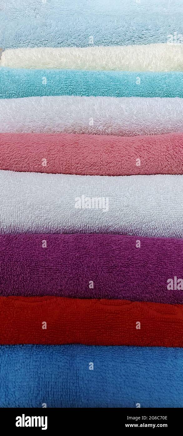 Gli asciugamani in spugna di cotone multicolore sono impilati Foto Stock