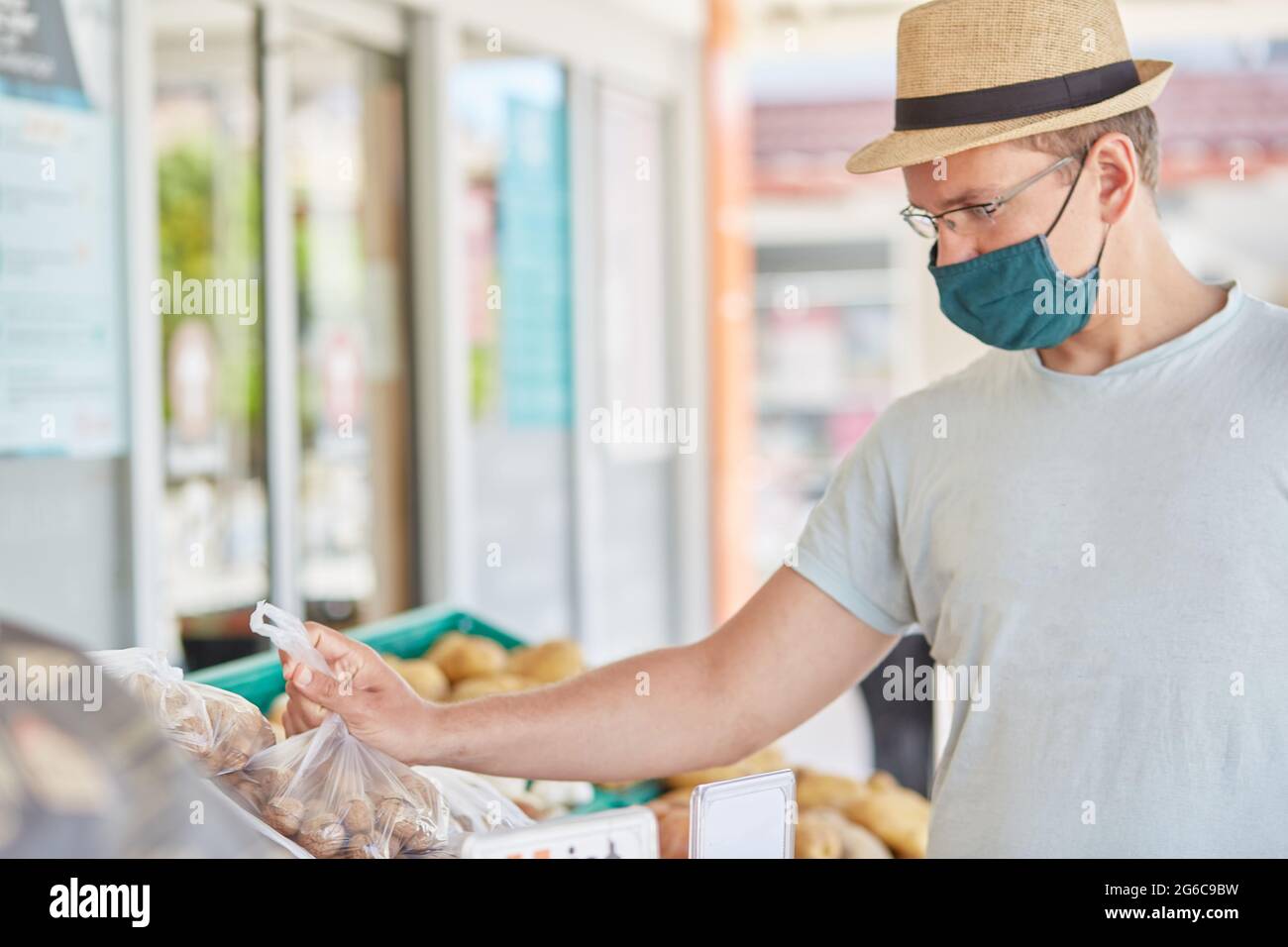 L'uomo in una maschera compra le verdure ad un mercato dell'agricoltore di strada. Concetto di quarantena del coronavirus. Foto di alta qualità Foto Stock