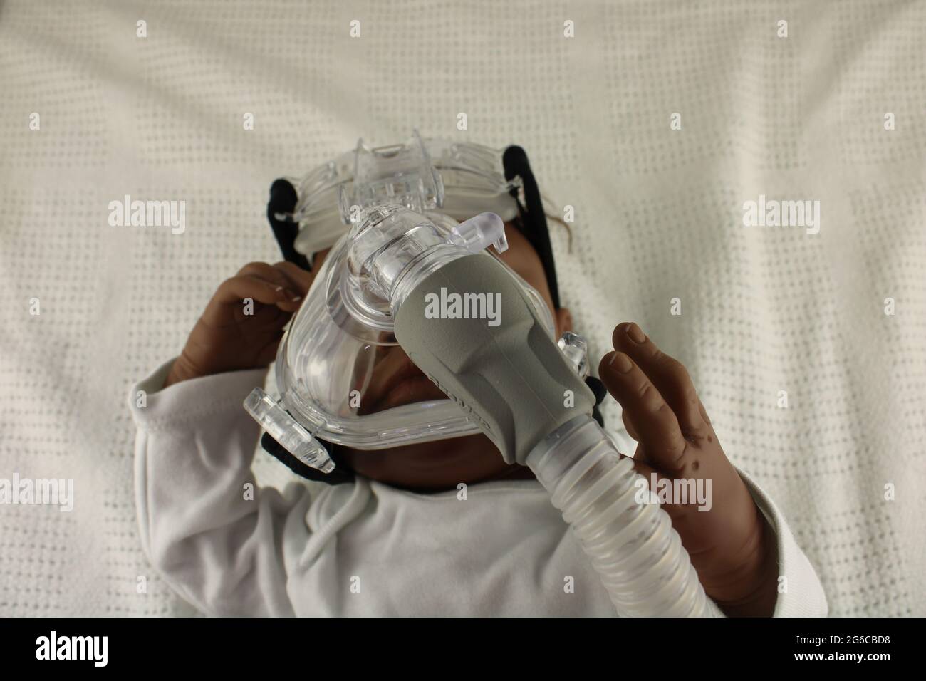 Bambino afroamericano che indossa una maschera nebulizzatrice. Concetto di asma infantile e concetto di virus respiratorio sinciziale, rappresentato da una bambola rinata. Foto Stock