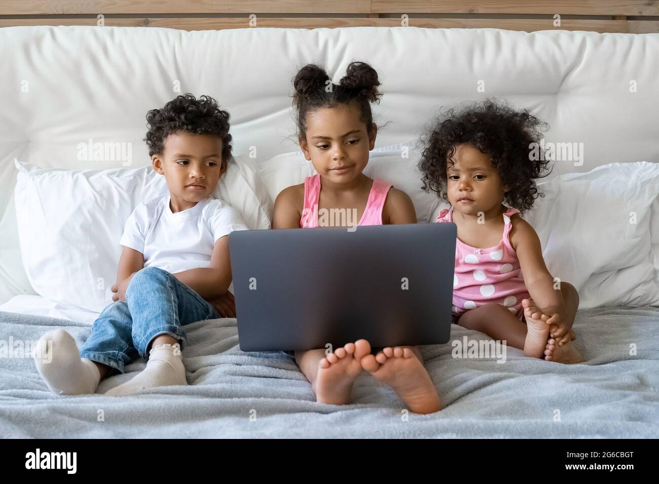 Tre bambini afro-americani di età diversa che guardano video su un computer portatile Foto Stock