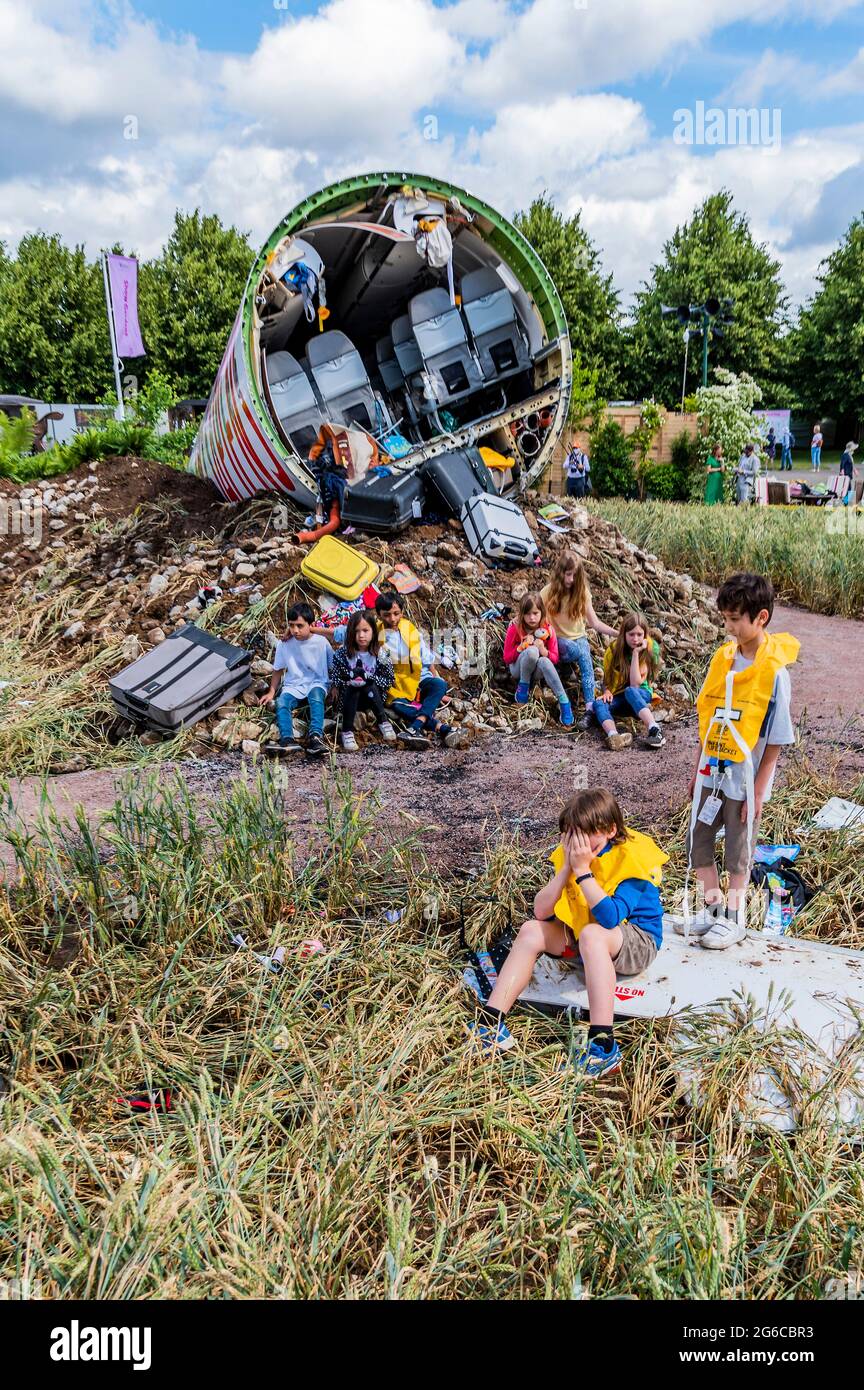 Londra, Regno Unito. 5 luglio 2021. I bambini in giubbotti sgonfi emergono provvisoriamente dal relitto dell'aereo schiantato - rappresentano i sopravvissuti e sono la nuova generazione che affronterà questa 'minaccia di estinzione'. Estinzione progettata da Felicity o'Rourke, un Global Impact Garden, che affronta la sesta minaccia di estinzione di massa per il nostro pianeta, causata dal nostro continuo sfruttamento e distruzione delle sue risorse naturali. Era precedentemente un pilota della linea aerea per Easyjet prima che diventasse un progettista del giardino e una campagna ambientale. Hampton Court Garden Festival - credito: Guy Bell/Alamy Live NE Foto Stock