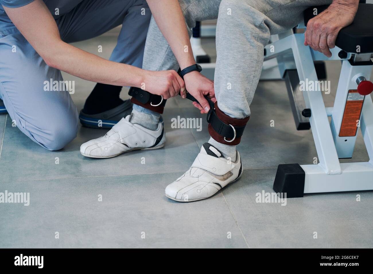 Medico che fissa la fascetta sulla caviglia sinistra del paziente Foto Stock