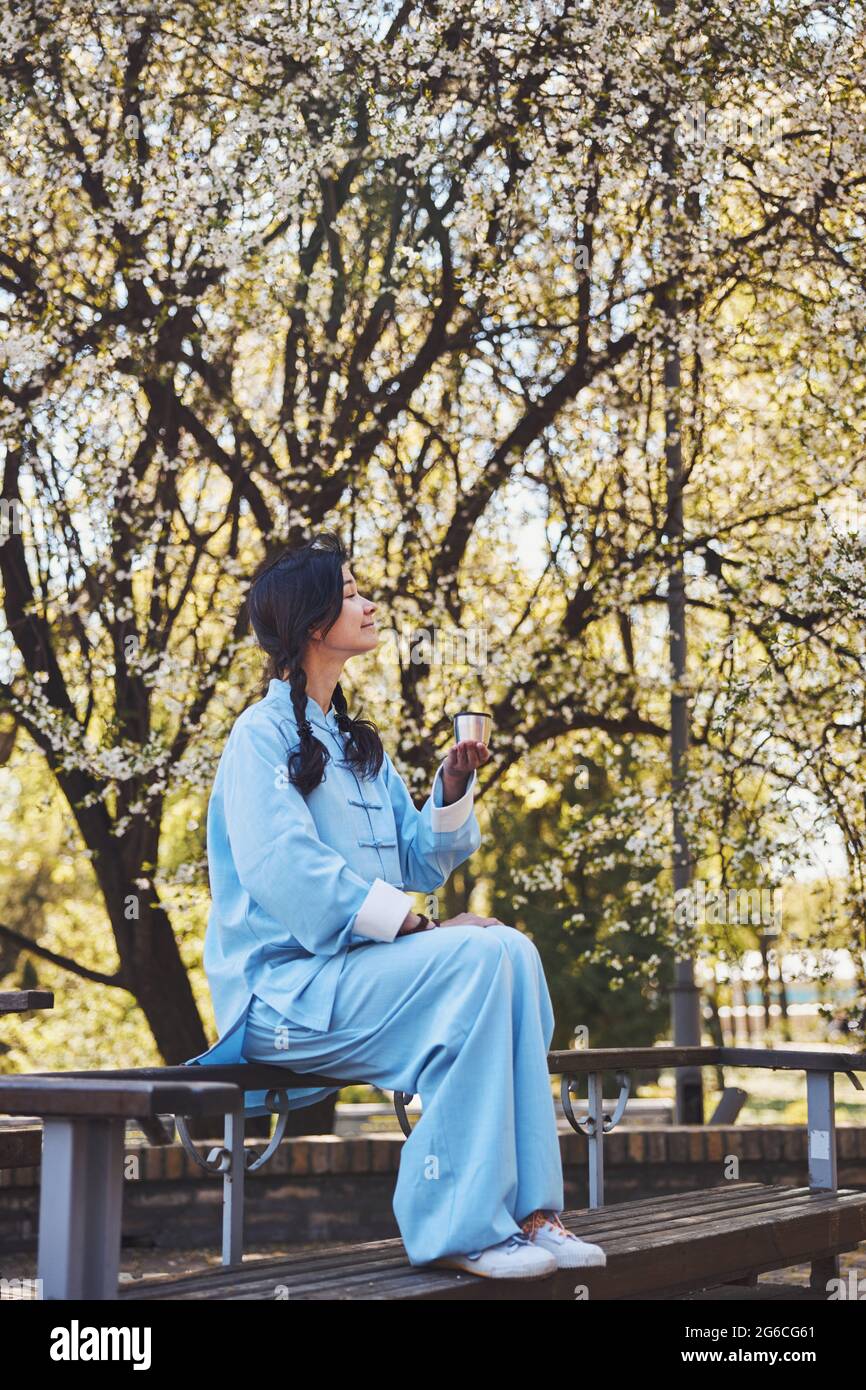 Donna in uniforme kung fu godendo la natura mentre beve il tè Foto Stock