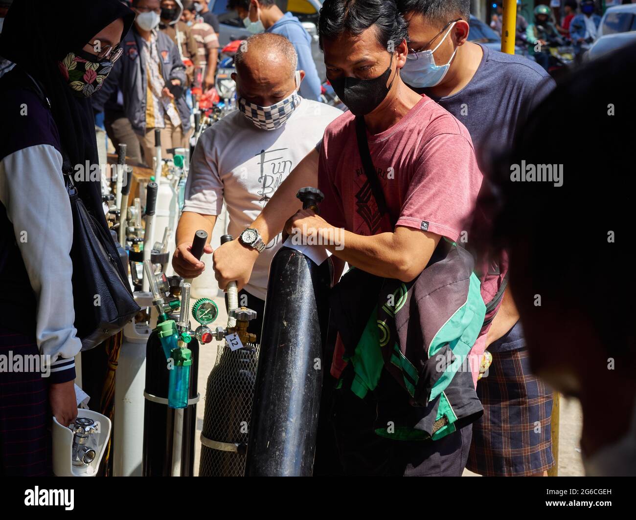 Coda di residenti che desiderano riempire le bombole di ossigeno. La domanda di bombole di ossigeno e ricariche per esigenze mediche domestiche è aumentata. Ciò è parallelo all'aumento dei casi di Covid-19 in Indonesia nelle ultime settimane. Come è accaduto in uno dei magazzini di rifornimento di ossigeno a Manggarai, nel sud di Giacarta, decine di residenti erano disposti a fare la coda per ore solo per riempire le bombole di ossigeno. Essi cercano questi articoli per fornire ossigeno per la loro famiglia che stanno subendo un trattamento indipendente a casa, perché quasi ogni singolo ospedale sono completamente caricati, ha detto uno di residenti. Tuttavia, non solo alcuni residenti Foto Stock