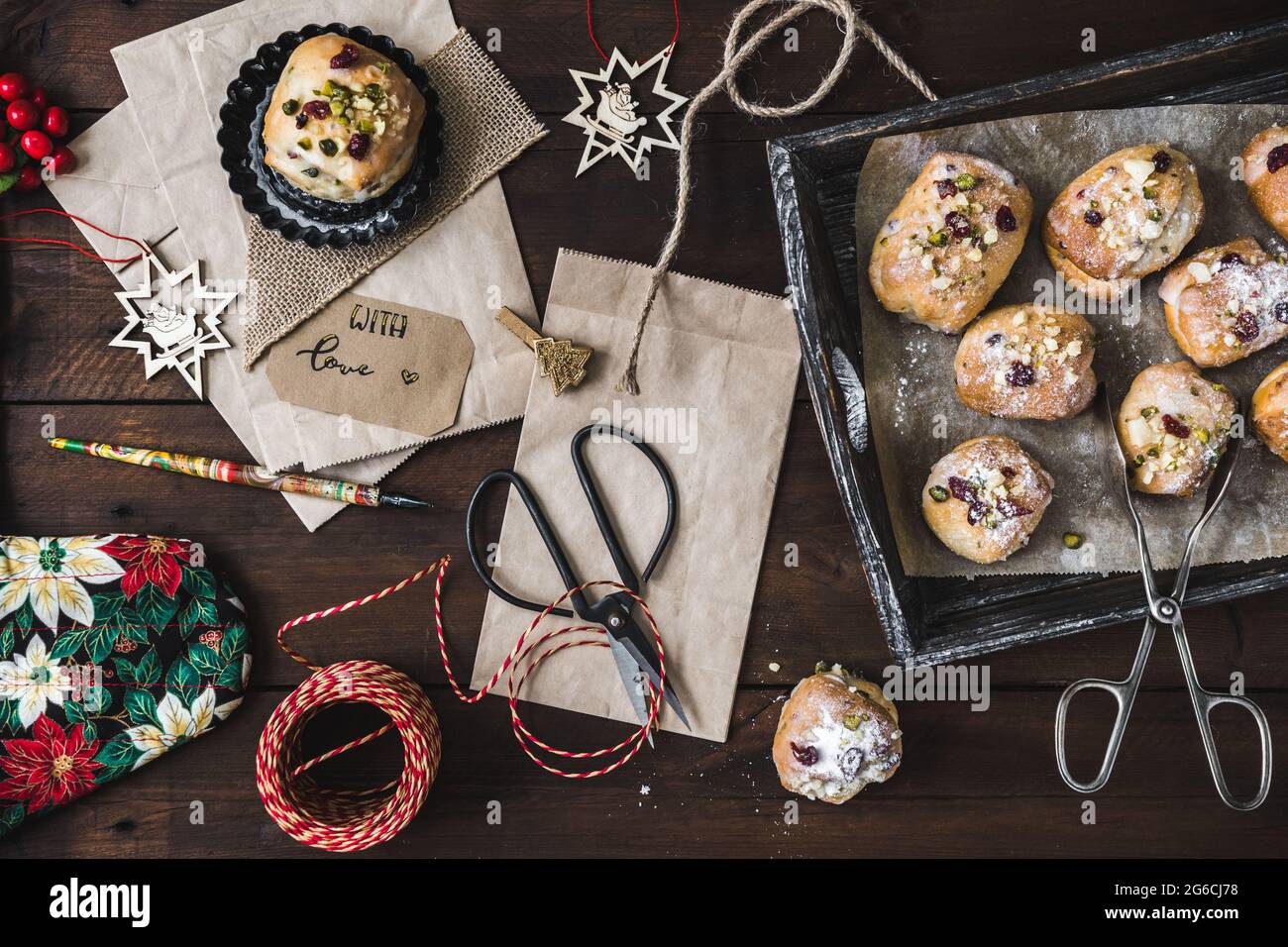 Scena per regali in Avent con mini stollen, sacchetti di carta, forbici, porta penna e nastro regalo su legno scuro Foto Stock