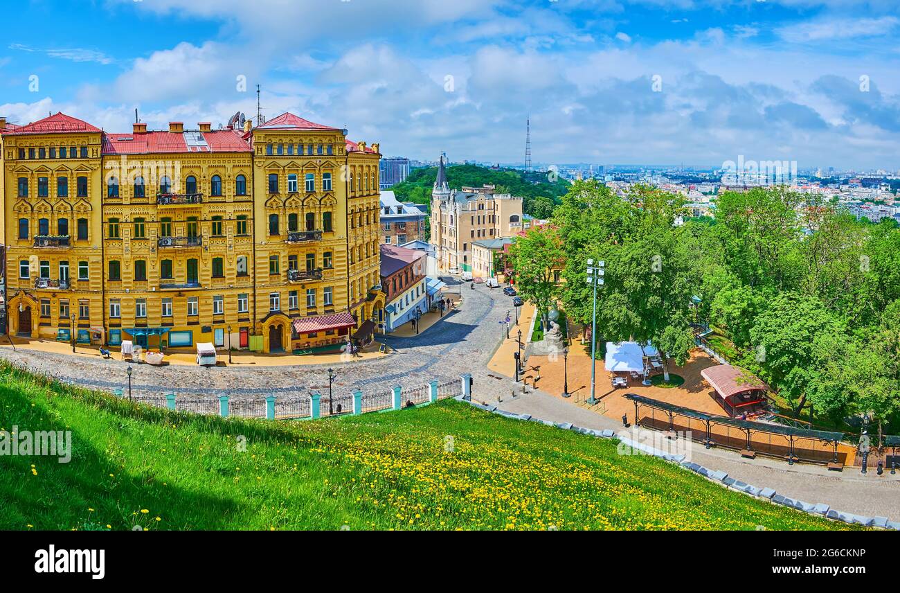 Panorama con il pendio verde di Andrew's Hill, coperto di erba e dandelioni, edifici storici della discesa di Andrew, Kiev, Ucraina Foto Stock