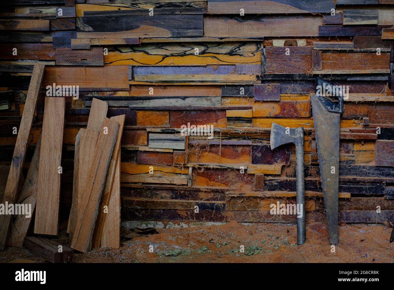 L'ascia e la sega a mano in metallo che poggiano contro vecchie pareti sono fatte di diversi tipi di legno Foto Stock