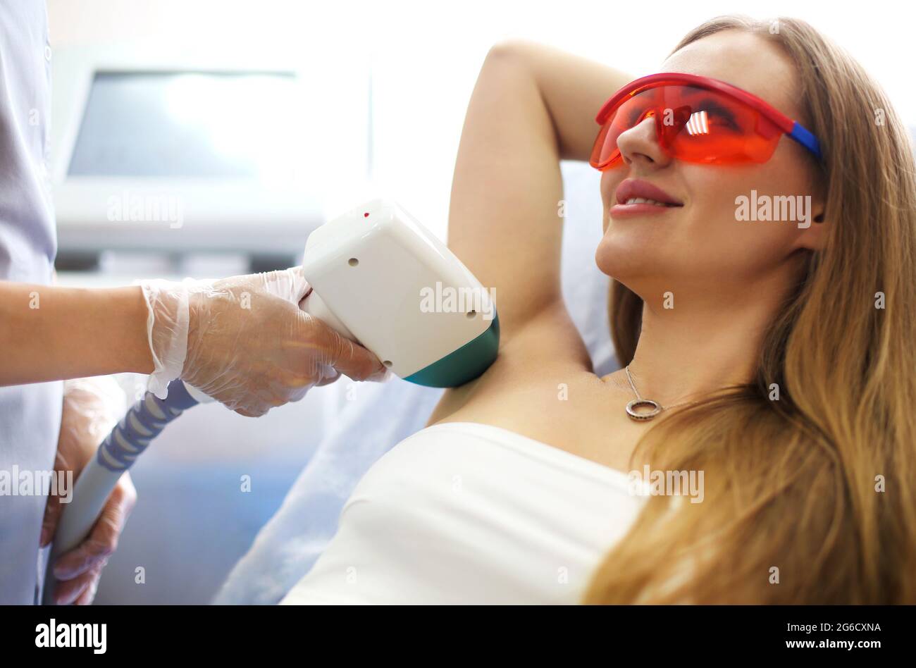 Dall'alto della cliente femminile sdraiata sul divano in bellezza salone durante l'epilazione laser delle ascelle Foto Stock