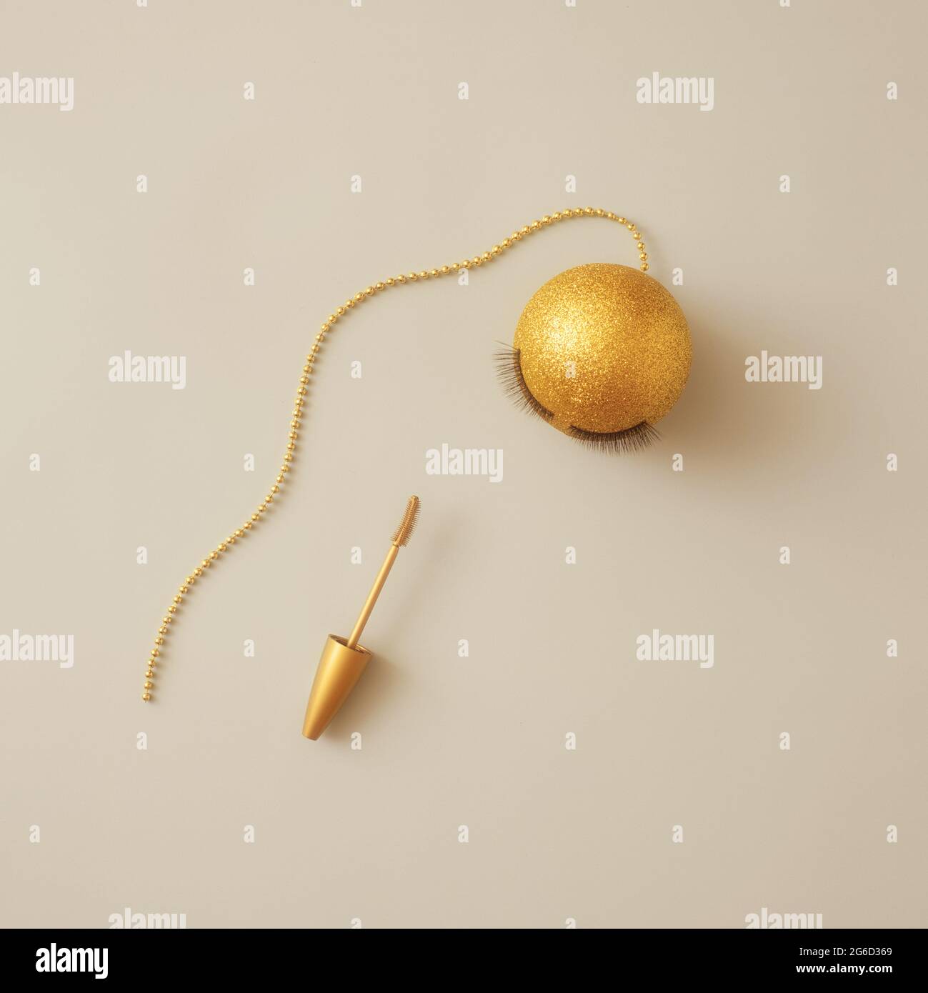 Minimalismo. Sfondo di Natale. Palla di Natale di colore oro e mascara su sfondo beige. Trucco di Capodanno. Posata piatta cartolina Foto Stock