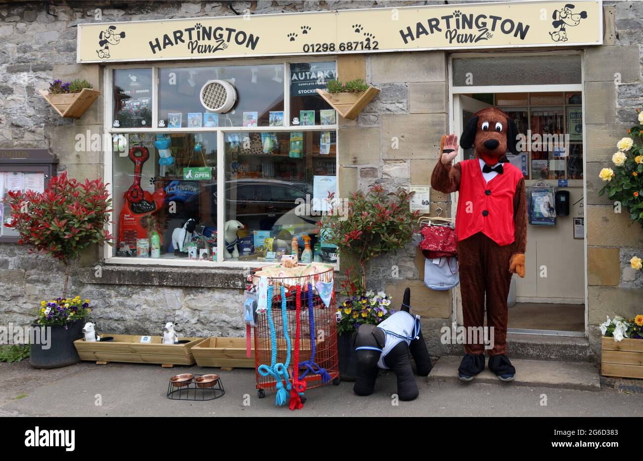 Hartington, Peak District, Derbyshire, Inghilterra, UK - UN uomo vestito da cane pubblicizza un negozio di animali nel villaggio Foto Stock