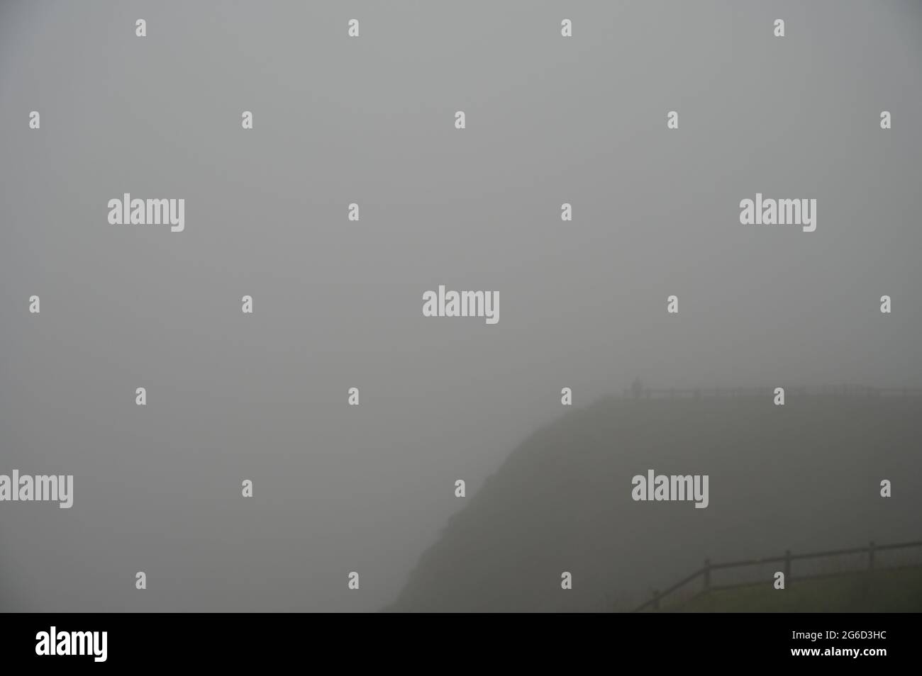 Persona misteriosa sul bordo della scogliera. Offuscato dalla nebbia pesante. Molto spazio vuoto. Foto Stock