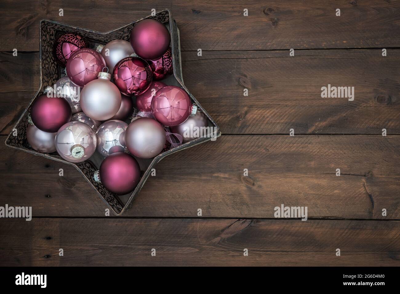 Ciotola a forma di stella piena di baubles di natale rosa e argento. Su sfondo di legno con spazio di copia. Foto Stock