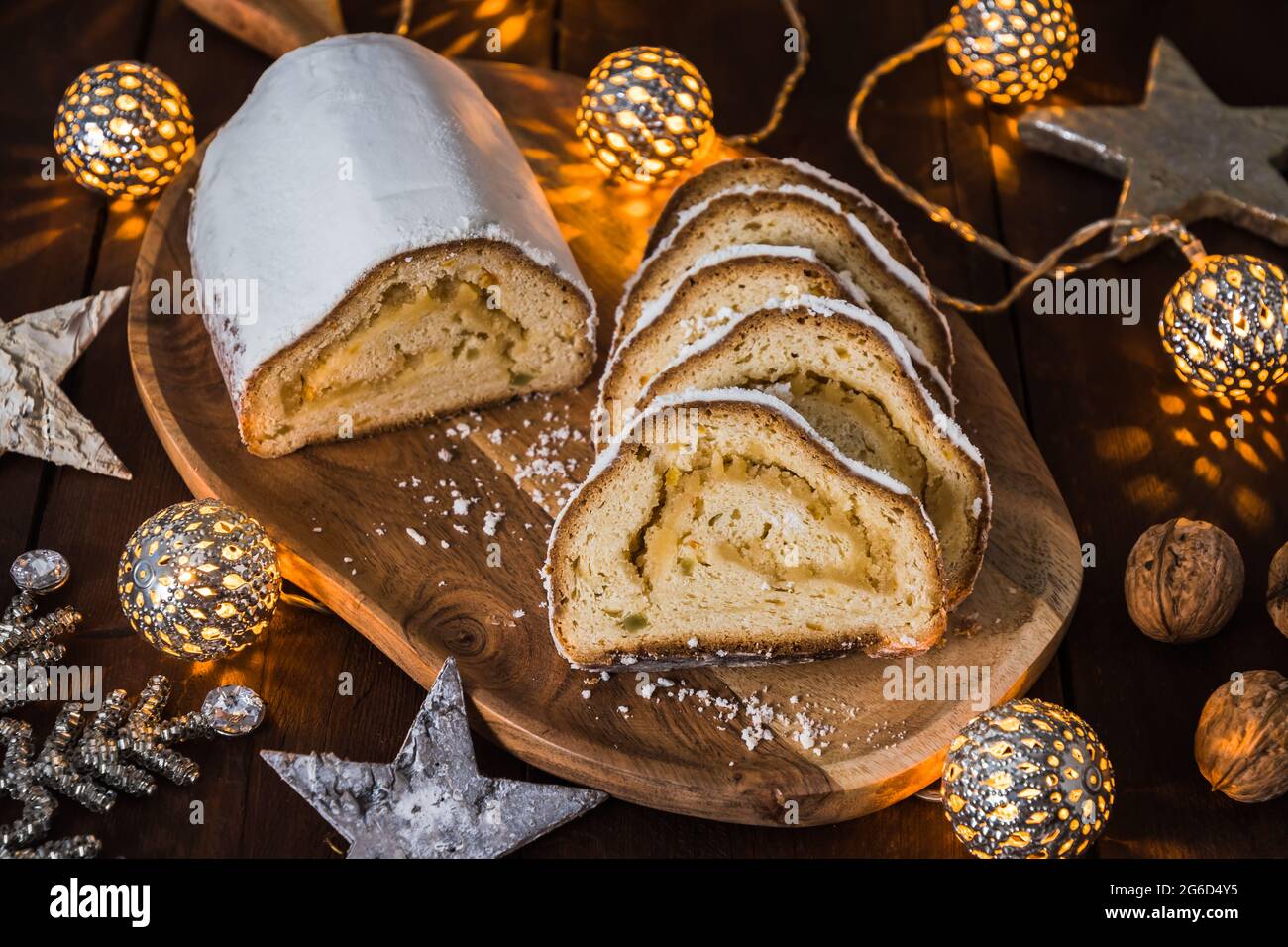 Natale stollen su una tavola di legno, luci e decorazione di natale sullo sfondo di legno, tradizionale torta di natale tedesca Foto Stock