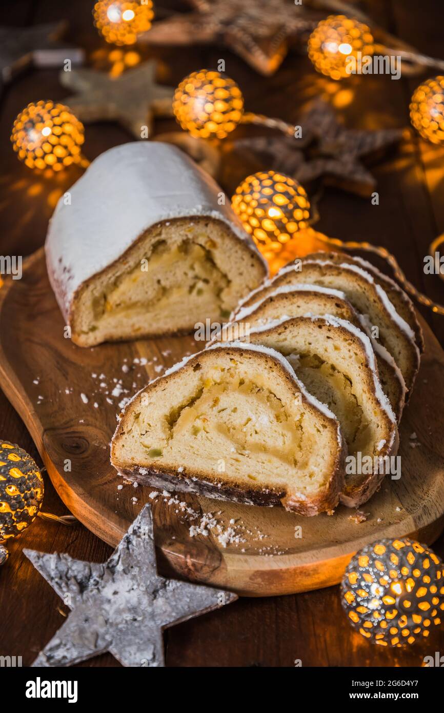 Natale stollen su una tavola di legno, luci e decorazione di natale sullo sfondo di legno, tradizionale torta di natale tedesca, verticale stock foto Foto Stock