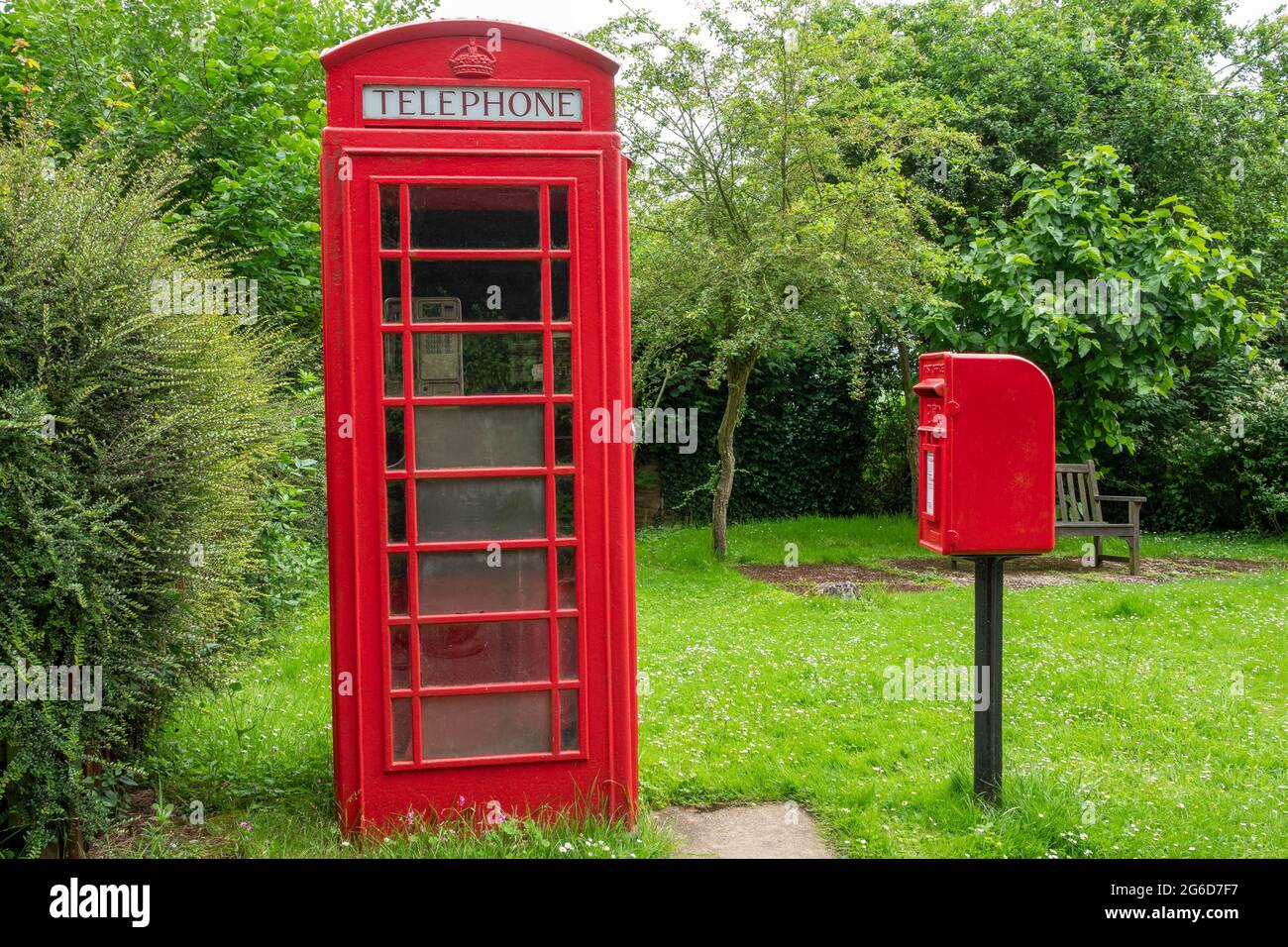Una scatola telefonica rossa K6 e una scatola di distacco in ghisa montata su palo rosso in un ambiente rurale Foto Stock