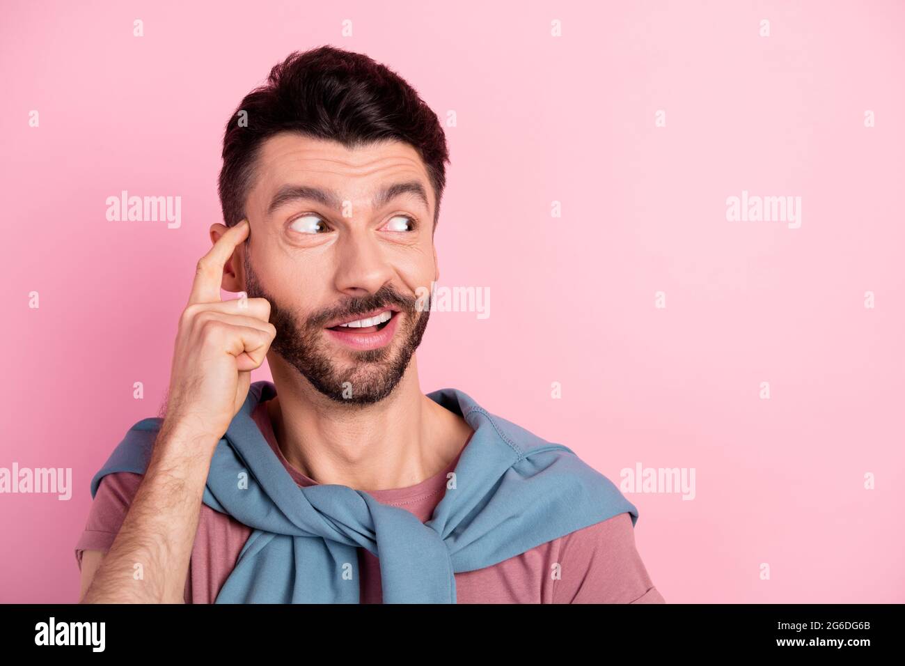 Foto di mentalità giovane ragazzo stupito sguardo vuoto spazio sogno tenere dito tempio isolato su sfondo di colore rosa Foto Stock