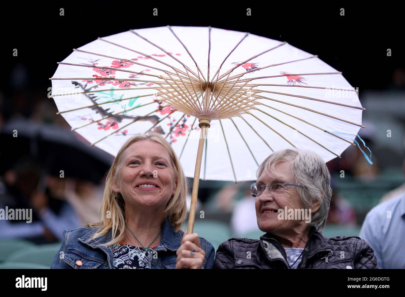 Gli Specatatori usano un ombrello ornato sul campo 1 il giorno 7 di Wimbledon all'All England Lawn Tennis and Croquet Club, Wimbledon. Data immagine: Lunedì 5 luglio 2021. Foto Stock