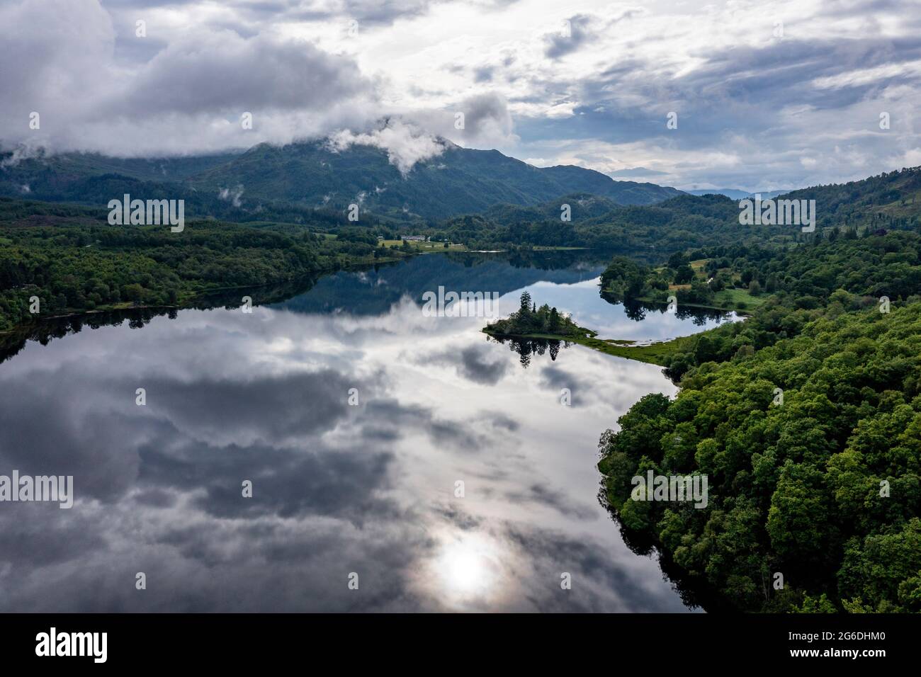 Loch Achray, Loch Lomond e Trossachs National Park, Scozia, Regno Unito. 4 luglio 2021. Nella foto: Loch Achray si trasforma in uno specchio che riflette la straordinaria bellezza naturale dell'area con l'hotel Loch Achray sullo sfondo ai piedi delle montagne. Credit: Colin Fisher/Alamy Live News Foto Stock