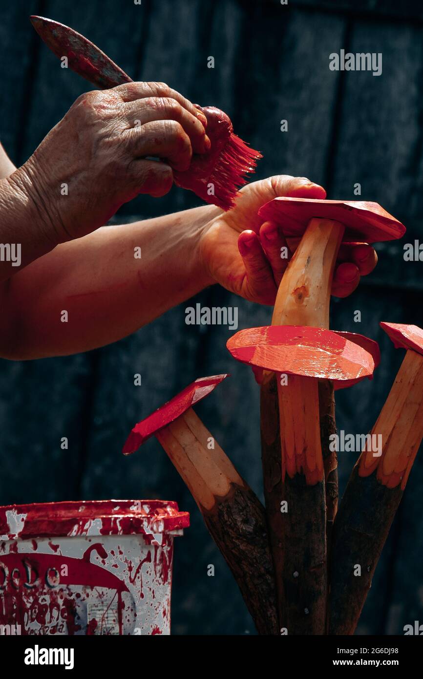 Scultura rustica in legno. Le mani della donna lavorano su un souvenir fatto di legno in uno sfondo esterno rustico. Foto Stock