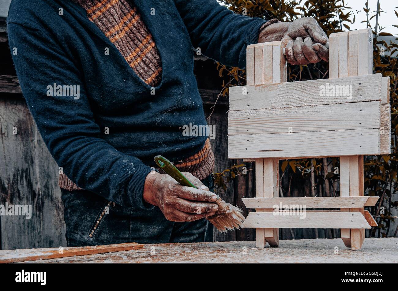 Vecchie mani di craftswoman che dipingano un oggetto di legno Foto Stock